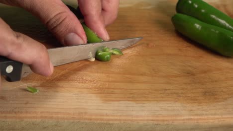 Hands-dicing-a-jalapeno-chili-on-a-cutting-board