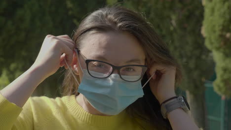 Slow-motion-shot-of-young,-Caucasian,-millennial-woman-with-glasses-putting-her-protective-mask-on