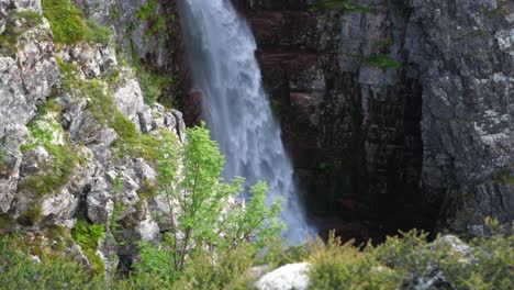 Arriba,-Incline-Hacia-Abajo,-Toma-Amplia-De-La-Gloriosa-Cascada-Njupeskärs-Rodeada-De-Exuberante-Vegetación-Y-Cañón-Rocoso-En-El-Parque-Nacional-Fulufjällets,-Suecia