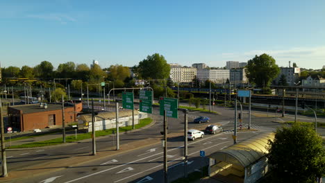 Daytime-Scene-In-Gdynia,-Poland---Few-Cars-On-The-Road-And-Train-Running-On-The-Railway---descending-drone-shot,-slow-motion