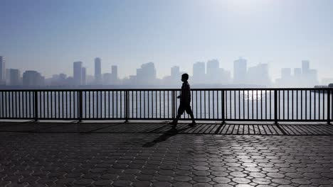 Silhouettes-of-a-10-year-old-boy-having-his-morning-walk-in-a-foggy-morning-at-Khalid-Lake-in-Sharjah,-United-Arab-Emirates,-4K-Video