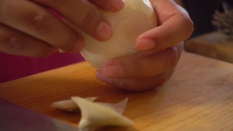 Peeling-an-onion-on-a-cutting-board
