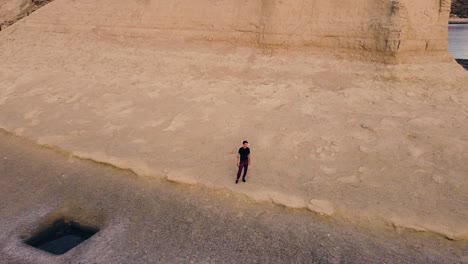 Attractive-Young-Man-Standing-Next-To-A-Coastal-Cliff-At-Sunset---Aerial-Drone-Shot