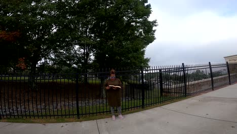Black-woman-standing-by-iron-fence-on-a-cloudy-day-reading-bible