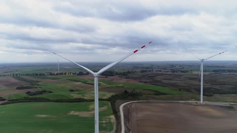 Farm-Windmills-Turned-Off-In-Green-Fields-On-A-Cloudy-Day-In-Kwidzyn,-Poland---Drone-Shot