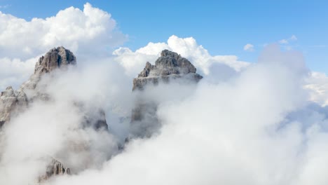 Drone-Aerial-in-the-white-clouds-with-mountains-peaking-through,-Tre-Cime-di-Lavaredo