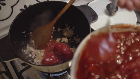 Adding-fresh-tomato-sauce-into-cooking-hot-pot-on-a-gas-stove