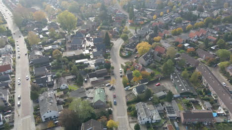 Stunning-aerial-of-beautiful-suburban-town-with-a-car-driving-over-road