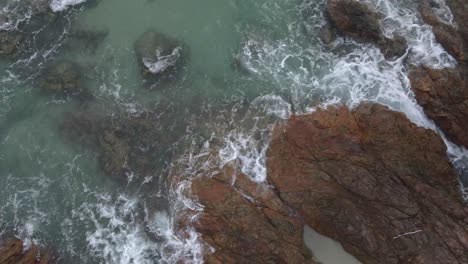 Trucking-birds-eye-view-drone-shot-of-tropical-coastline-with-granite-rock-and-ocean-waves-and-jungle
