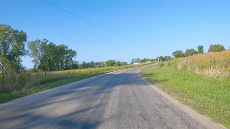 Double-time-POV-while-driving-around-a-bend-in-a-county-paved-road-in-rural-Iowa-in-early-autumn