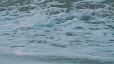 close-up-of-the-foam-of-the-waves-crashing-on-the-sand-of-the-beach-in-slow-motion