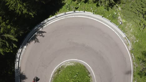 Top-down-of-a-cyclist-on-a-hairpin-turn-road-minimalist,-Italy