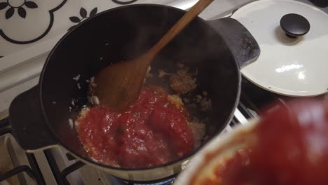 Adding-fresh-tomato-sauce-into-cooking-hot-pot-on-a-gas-stove
