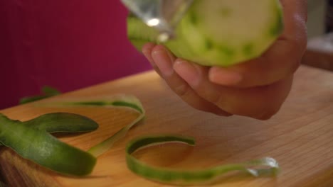 Peeling-a-cucumber-with-a-peeler-on-a-cutting-board