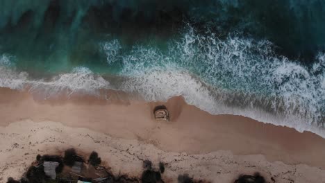 Drone-flying-down-over-Nunggalan-beach-in-Bali,-South-Kuta while-the-waves-are-rolling