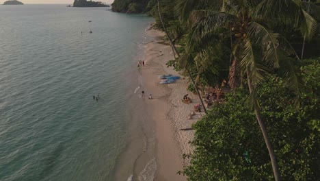 Tropical-Island-drone,-bird’s-eye-view-down-shot-with-lush-green-rain-forest-and-tropical-palm-trees-with-white-sand-beach-and-small-beach-bars-and-restaurants-and-bungalows