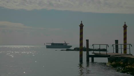 Handaufnahme-Des-Malerischen-Docks-Und-Eines-Passagierboots,-Das-Langsam-Auf-Dem-Gardasee,-Italien,-Fließt