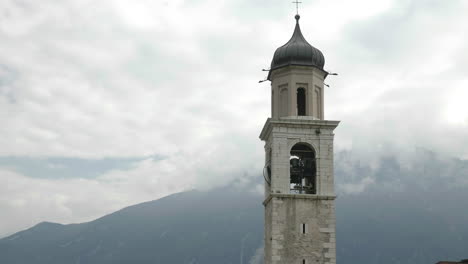 Bell-toll-in-a-church-tower-located-in-a-heaven-like-location-with-majestic,-misty-mountains-in-the-background