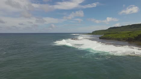 Flying-over-the-coast-as-waves-crash-on-a-tropical-island