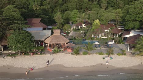 Tropical-Island-drone,-bird’s-eye-view-down-shot-of-small-resort-with-swimming-pool-with-tropical-palm-trees-with-white-sand-beach-and-small-beach-bar,-restaurant,-bungalows-on-Koh-Chang-Thailand