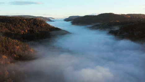 Luftflug-über-Dichtem-Nebel,-Der-Bei-Sonnenaufgang-Bewaldete-Berge-Umhüllt
