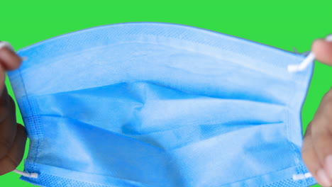 Mann-Hält-Und-Trägt-Blaue-OP-Maske-Gegen-Green-Screen-Chroma-Key