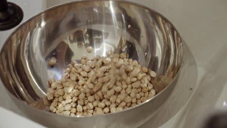 Putting-water-into-metal-bowl-full-of-chickpea-for-soaking