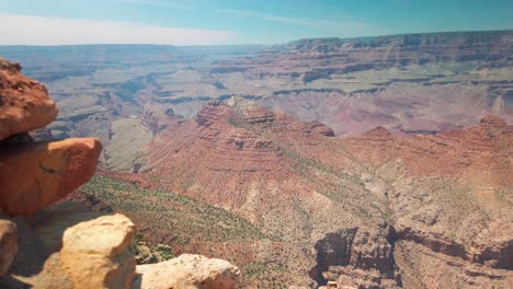 Kameraschwenk-Von-Den-Felsen-Im-Vordergrund,-Um-Den-Grand-Canyon-Im-Hintergrund-Zu-Enthüllen