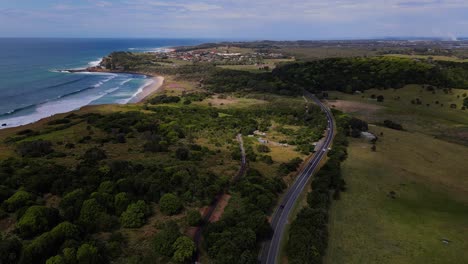 Vehicles-Driving-At-Coast-Road-By-Lush-Green-Fields---Seaside-Village-With-Ocean-Views---Lennox-Head,-NSW,-Australia