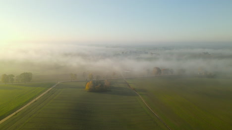 Low-Clouds-cover-Green-Pasture-Meadows-and-fields-during-magnificent-Sunrise,-Drone-Aerial
