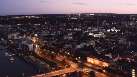 Mainz-Bei-Nacht-Durch-Eine-Drohne-In-Einer-Breiteren-Aufnahme,-Die-Sich-Nach-Sonnenuntergang-Dem-Stadtzentrum-Nähert,-Mit-Ein-Wenig-Nachglühen-Am-Himmel