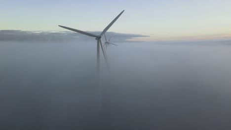 Flying-up-through-the-clouds-and-reveals-a-group-of-windturbines-in-the-low-fog
