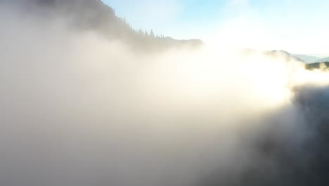 Flying-Into-Low-Clouds-in-Mountain-Valley-Under-Golden-Hour-Sunlight-on-Summer