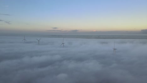 Wind-turbines-rotating-above-the-clouds-during-a-foggy-morning