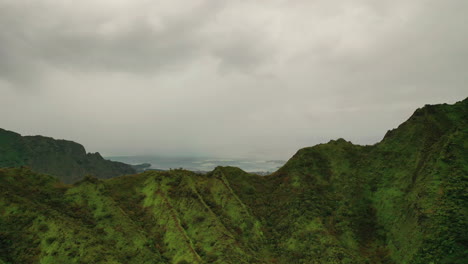 Reveladora-Toma-De-La-Isla-De-Oahu-Detrás-De-Una-Exuberante-Montaña-Rocosa-En-Hawaii---Dron-Aéreo