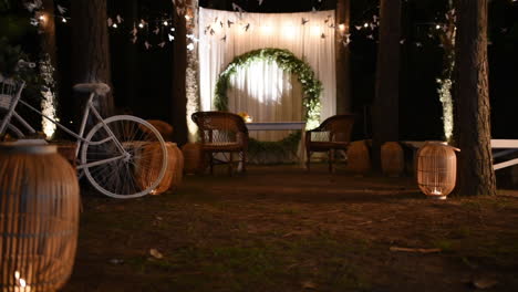 Elegante-Vintage-Nachthochzeitsarrangements,-Liebeslichtbuchstaben,-Altar-Und-Fahrrad-Unter-Romantischen-Lichtern-Auf-Bäumen-Im-Außenbereich,-Schwenkaufnahme