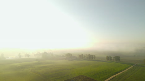 Aerial-shot-of-single-lone-house-in-rural-scenic-farmland-field-during-hazy-sunrise