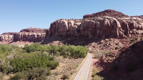 Utah-canyon-rock-faces-outside-Canyonlands-National-Park,-empty-road-and-cottonwoods-on-canyon-floor