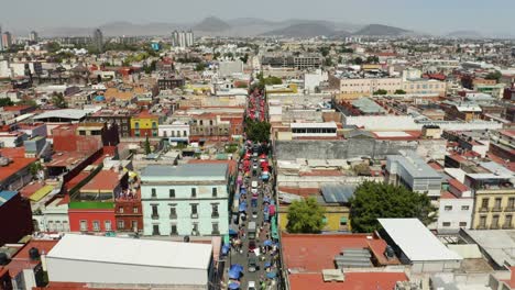 Traditional-Street-Market-in-Mexico-City,-Low-Aerial-View,-Crowded-Capital-City,-Dolly-Back