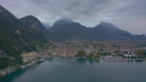 Aerial-shot-of-passenger-boat-pulling-out-of-the-Riva-Del-Garda-marina,-Italy