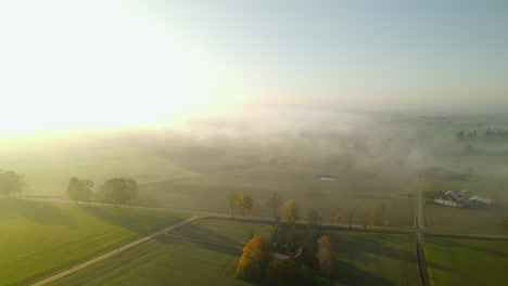 Beautiful-aerial-view-of-fog-rolling-over-rural-countryside-farmland-at-sunrise