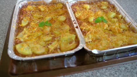 Two-Trays-Of-Freshly-Baked-Potatoes-With-Pork-Topped-With-Cheese---zoom-out-shot