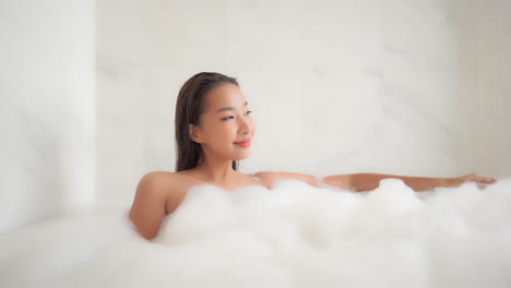 Beautiful-Asian-girl-Sitting-in-Foam-Bath-looking-aside,-portrait,-Static,-slow-motion