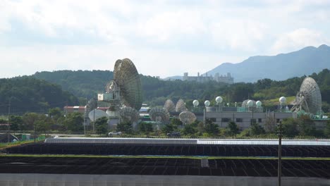 Daytime-KT-SAT-Satellite-Dishes-In-Geumsan-on-beautiful-mountain-background,-South-Korea