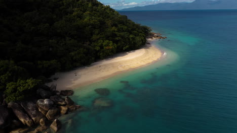 Wide-rotating-drone-shot-of-beach-on-Fitzroy-Island-with-woman-walking-on-sand