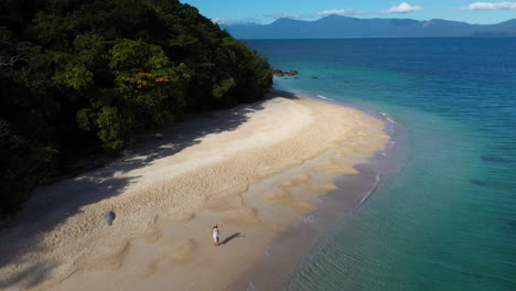 Revealing-drone-shot-of-woman-walking-in-the-water-at-Fitzroy-Island-Australia