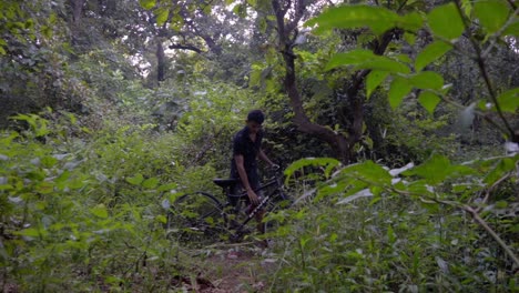 boy-man-walking-with-a-cycle-in-deep-jungle-slow-motion-drinking-water