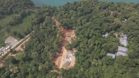 Aerial-drone-birds-eye-view-side-trucking-shot-of-land-clearing,-real-estate-development-in-the-tropical-forest-by-the-coast-on-an-Island-in-Thailand