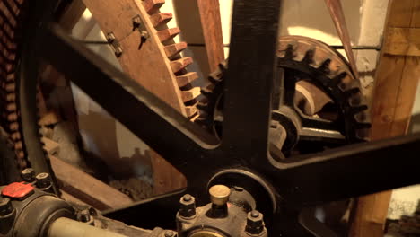Spinning-Cogwheels-Gear-Wheels-in-wooden-historical-old-Mill---Closeup-handheld-panning-right