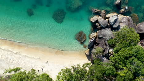 Descending-drone-shot-towards-beach-and-clear-blue-water,-Fitzroy-Island-Australia